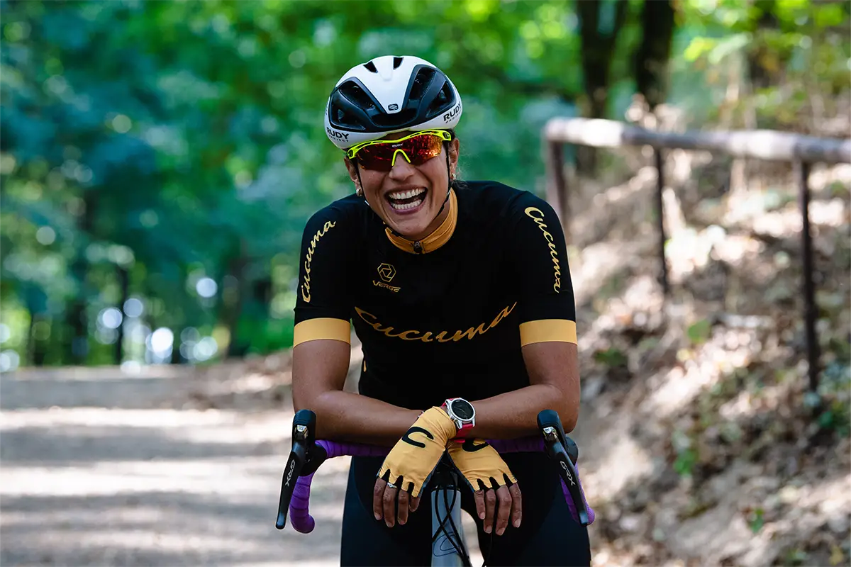 Lachende Frau lehnt sich entspannt auf ihr Gravel Bike während einer Pause im Wald